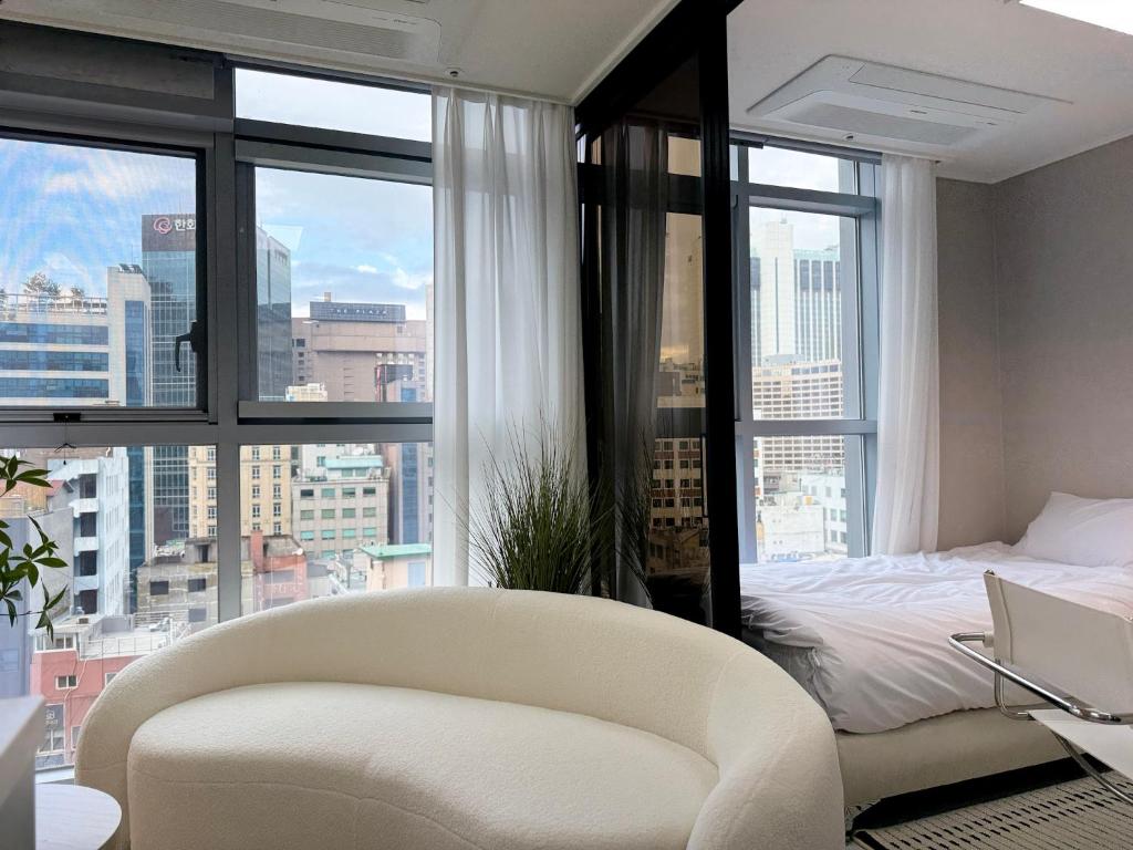a bedroom with a bed and a chair and windows at 2BR City Hall Station 6min, Myeongdong & Namsan Stay in Seoul