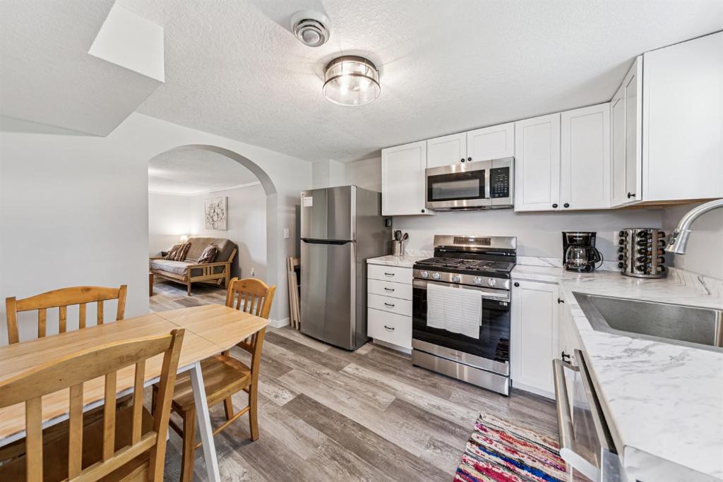a kitchen with white cabinets and a wooden table with a dining room at Cozy 2BR Garden Apartment Near Lake Pepin - Daisy in Pepin