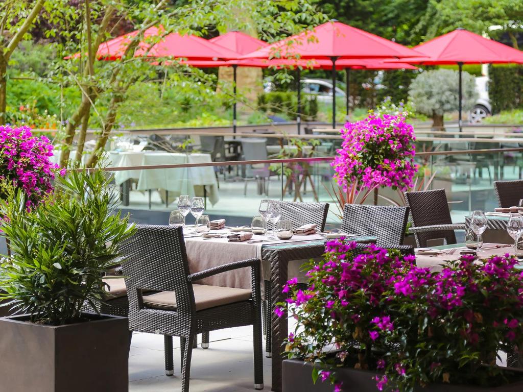 a table with chairs and pink flowers on a patio at Le Royal Hotels & Resorts Luxembourg in Luxembourg