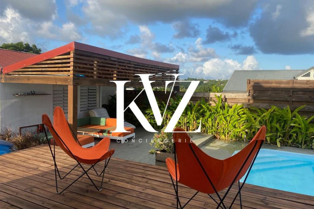 a deck with two chairs and a table and a pool at Villa design et piscine Le Gosier in Le Gosier