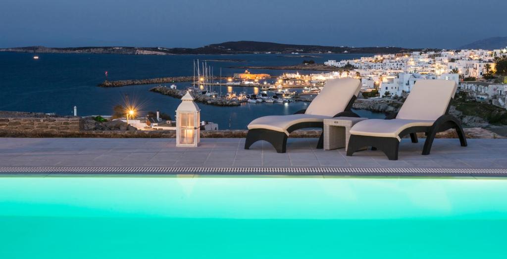 a pool with two chairs and a view of a harbor at Villa Irini in Naousa