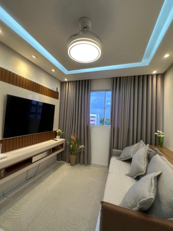 a living room with a large television and a bed at Flor da Amazônia 1 Belém - PA in Ananindeua