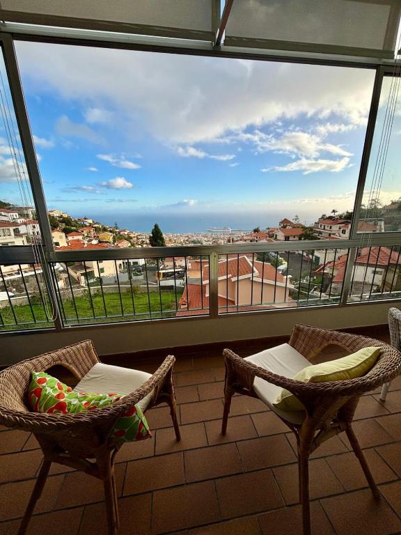 a balcony with two chairs and a view of a city at Santos Living Rentals in Funchal
