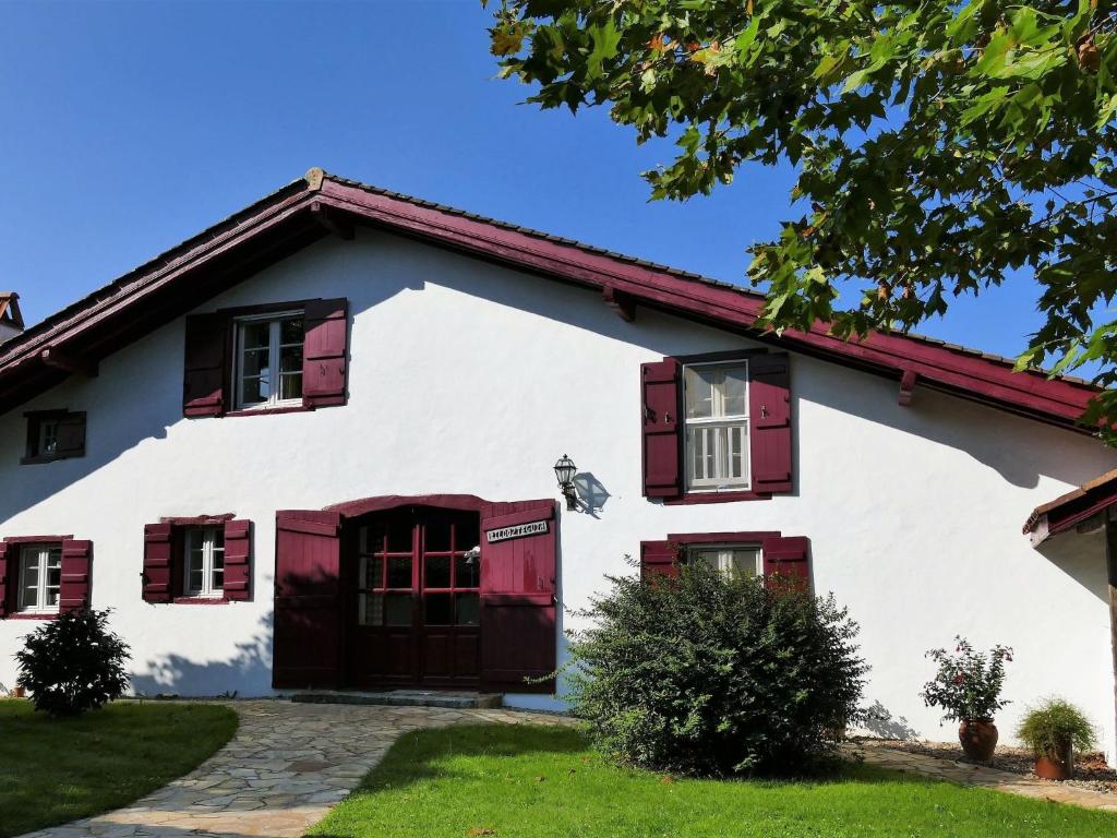 a white house with red shuttered windows at by Interhome in Louhossoa