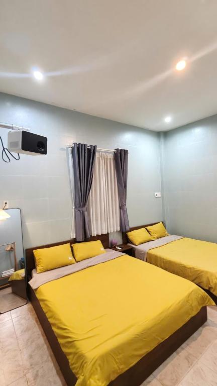 two beds in a room with yellow sheets at MOJA HOUSE l Homestay Huế in Thôn Dương Xuân Hạ
