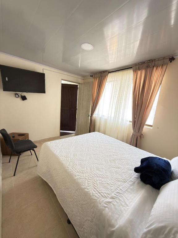 a bedroom with a large white bed and a window at Hotel Plaza de Toros in Manizales