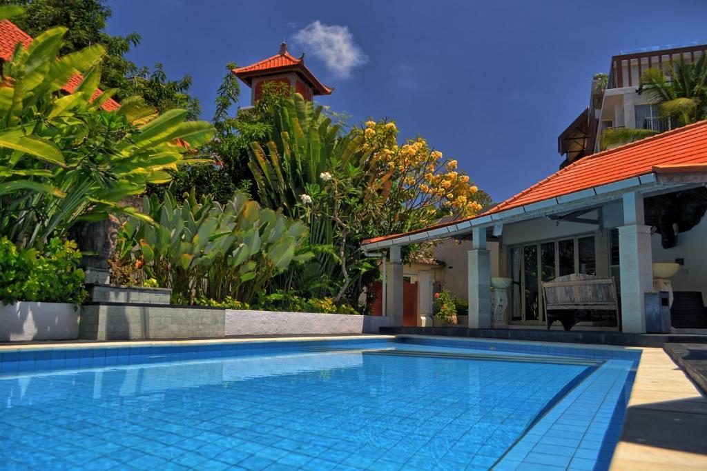 a swimming pool in front of a house at Grange Villa - Legian in Legian