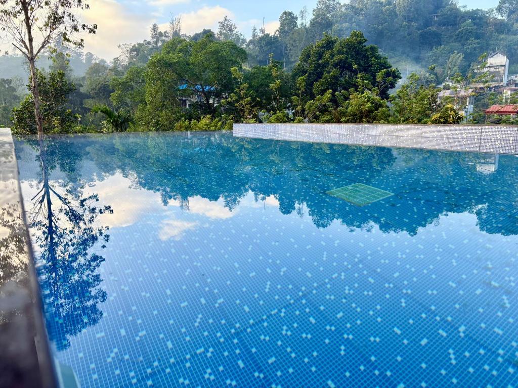 a swimming pool with blue water and trees in the background at Monaara Leisure - Ella in Ella
