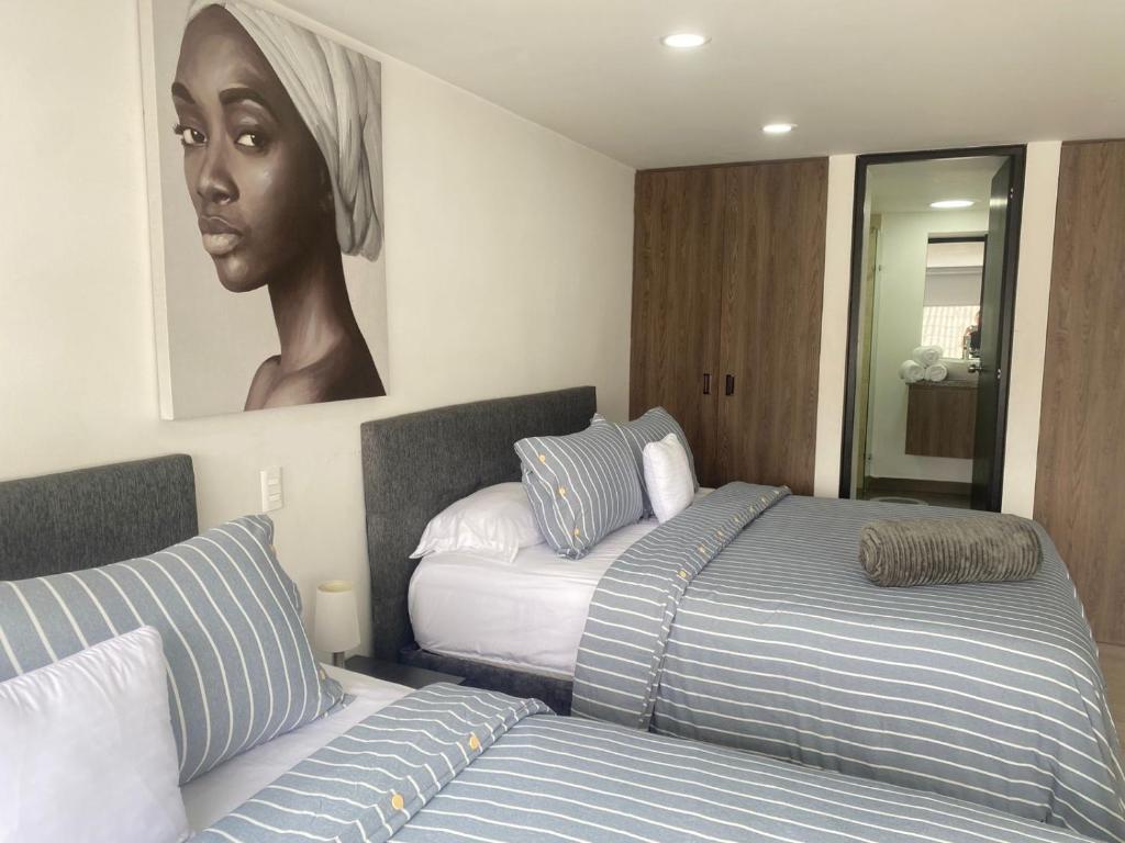 a bedroom with two beds and a painting on the wall at Spacio30 in Bogotá