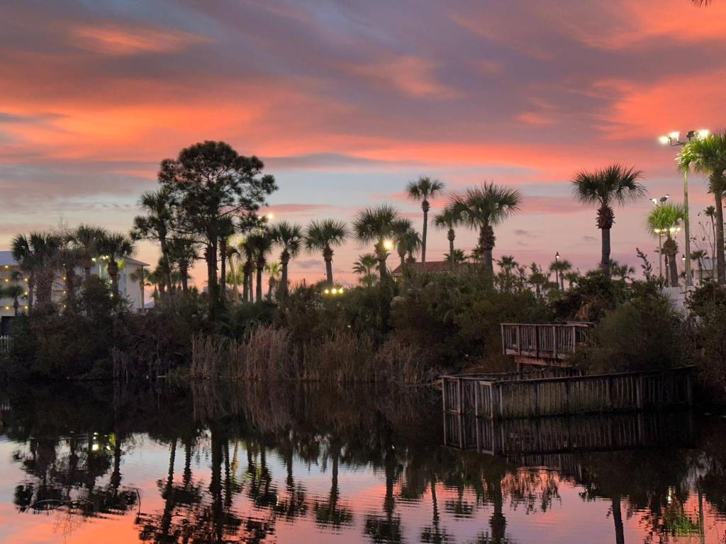 a sunset over a body of water with palm trees at Reef Retreat in Panama City Beach