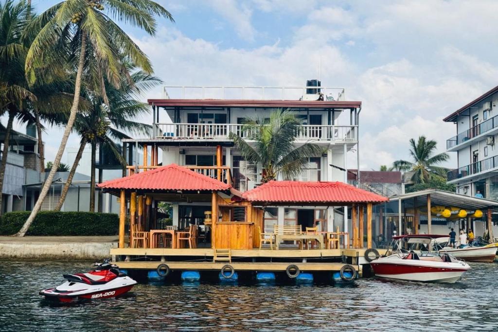 a house on a dock in the water with boats at Luthmin River View Hotel in Alutgama