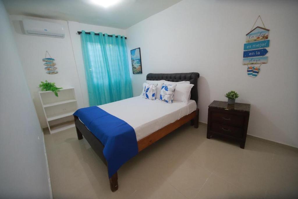 a bedroom with a bed with blue sheets and a nightstand at franchecis hostal cerca del mar in Juan Dolio