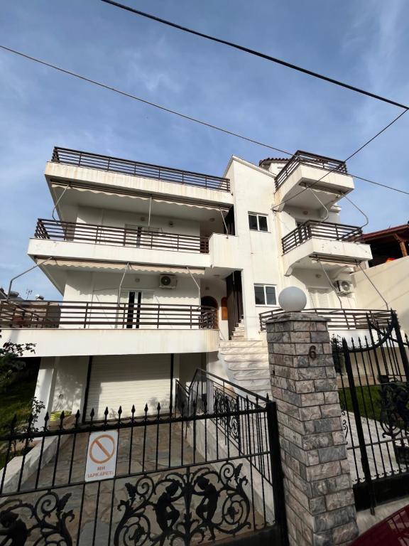 a white building with balconies and a gate at Zeus Beach Condo in Vernardhaíika