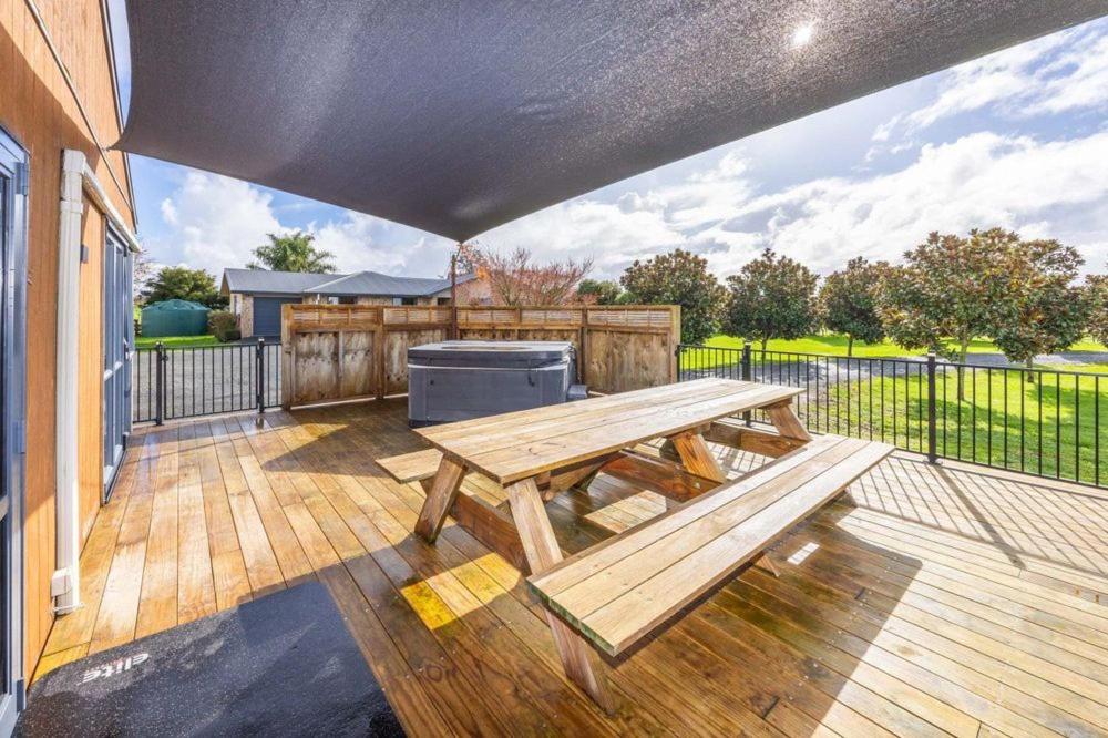 a wooden picnic table on a deck with a fence at Mill Road Retreat Ohaupo in Kaipaki