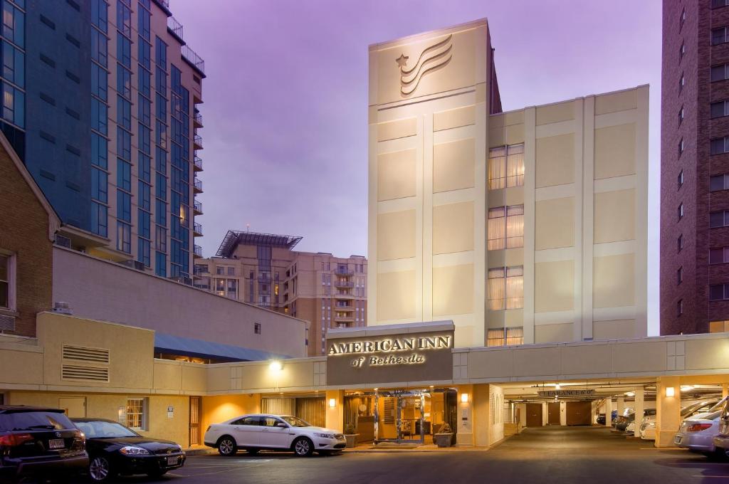 un bâtiment avec des voitures garées dans un parking dans l'établissement American Inn of Bethesda, à Bethesda