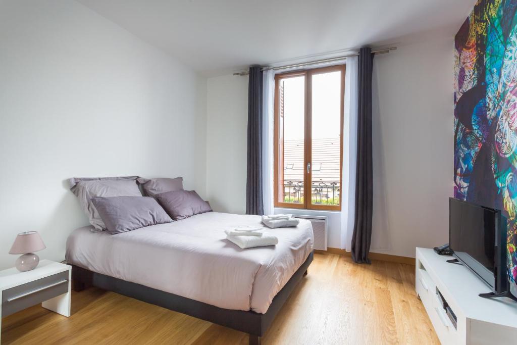 a white bedroom with a bed and a television at The Pearl in Vitry-sur-Seine