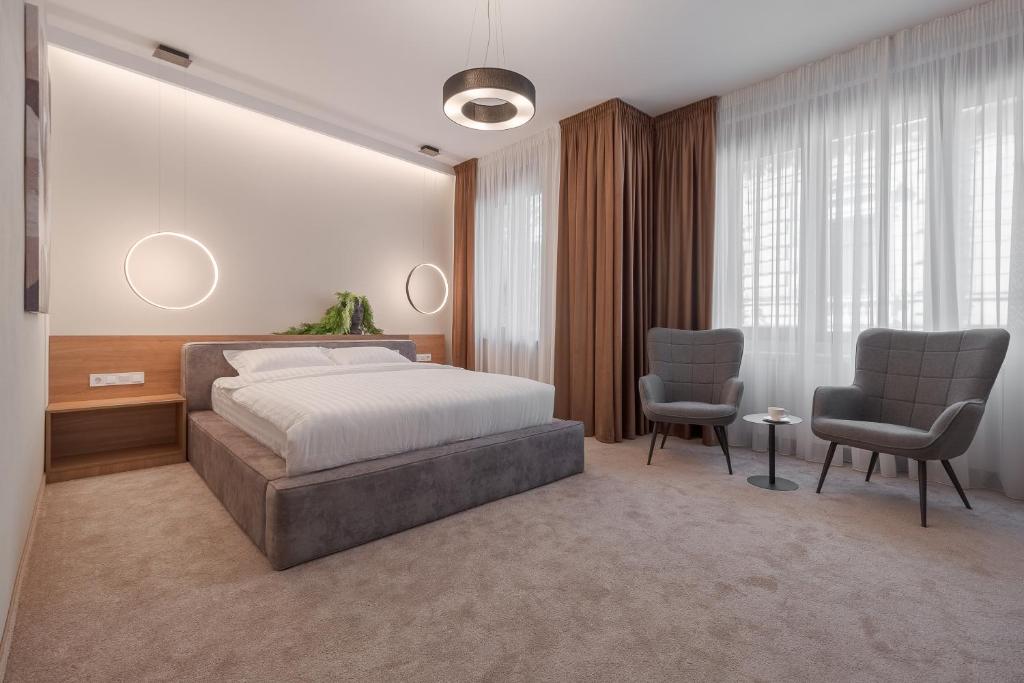 a bedroom with a bed and two chairs at Oasis Rooms Oradea in Oradea