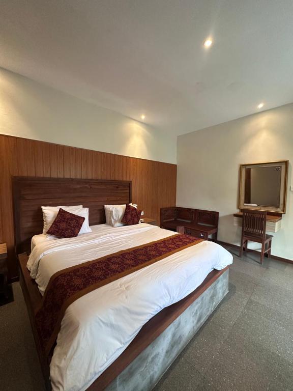 a bedroom with a large bed and a flat screen tv at Deswa inn in Ubud