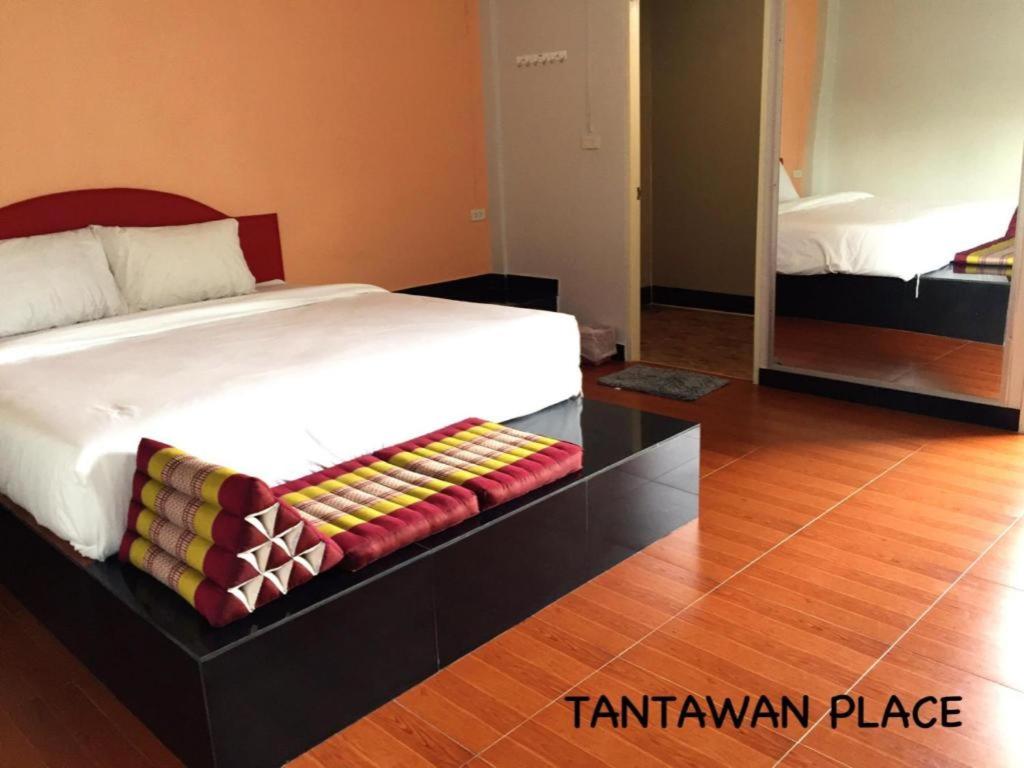 a large bed in a room with a wooden floor at Tantawan Place in Roi Et