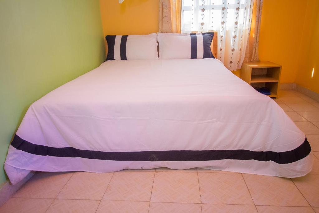 a bedroom with a large white bed with blue and white sheets at Airport Gate View Hotel in Nairobi