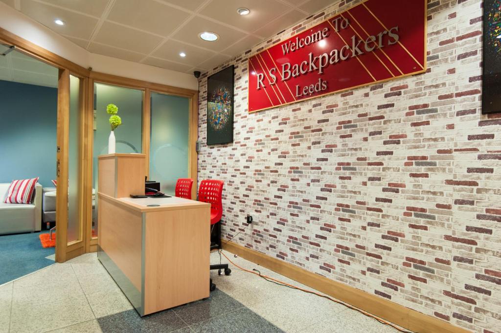 a reception area with a brick wall and a desk at Russell Scott Backpackers Hostel in Leeds