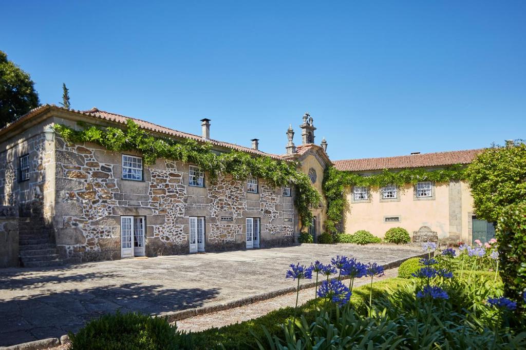 an exterior view of a stone building with flowers at Casa de Canedo in Celorico de Basto