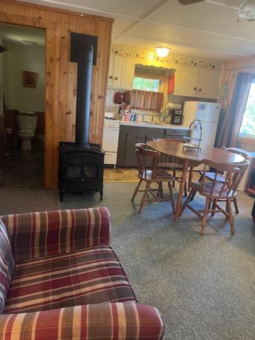 a living room with a table and a wood stove at Northwoods Lake Content Cabin in Saint Germain