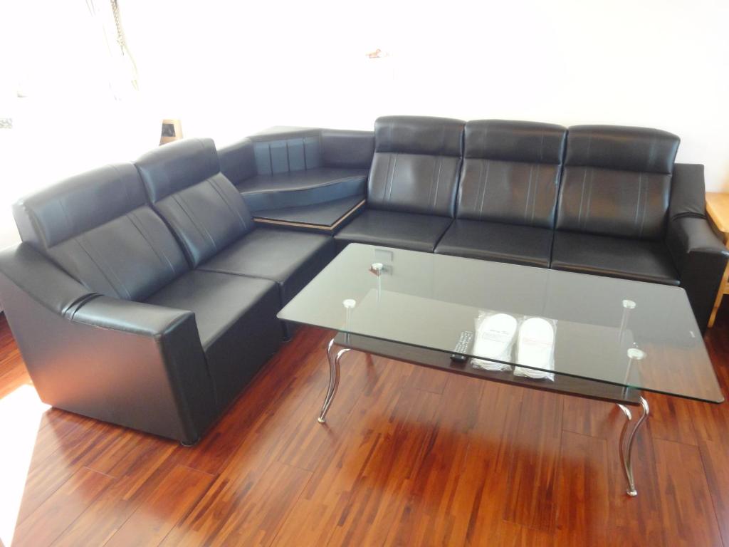 a black leather couch with a glass coffee table at Natural Residence B&amp;B in Tai&#39;an