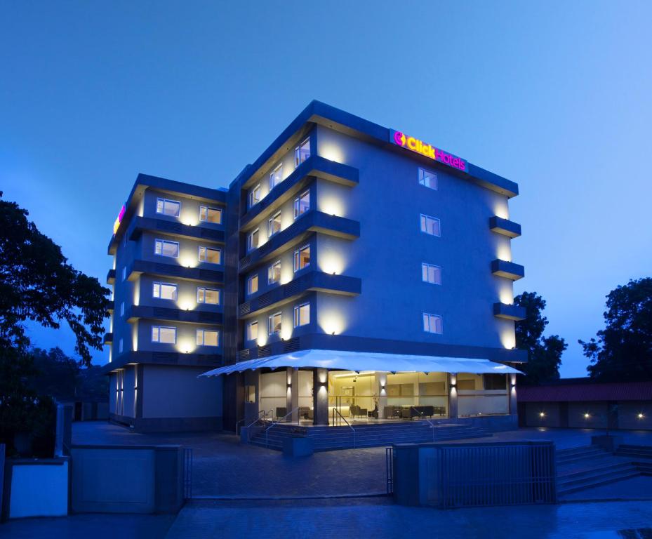 un bâtiment d'hôtel avec des lumières allumées la nuit dans l'établissement Click Hotel, Junagadh, à Junagadh