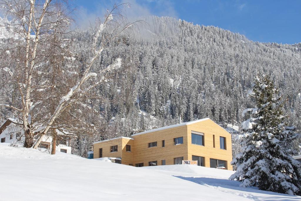 a house in the snow in front of a mountain at Ferienwohnung Aviez Savognin in Savognin