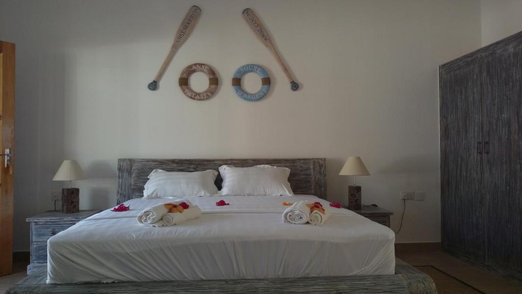 a bedroom with a bed with two towels on it at Coral Apartments in La Digue
