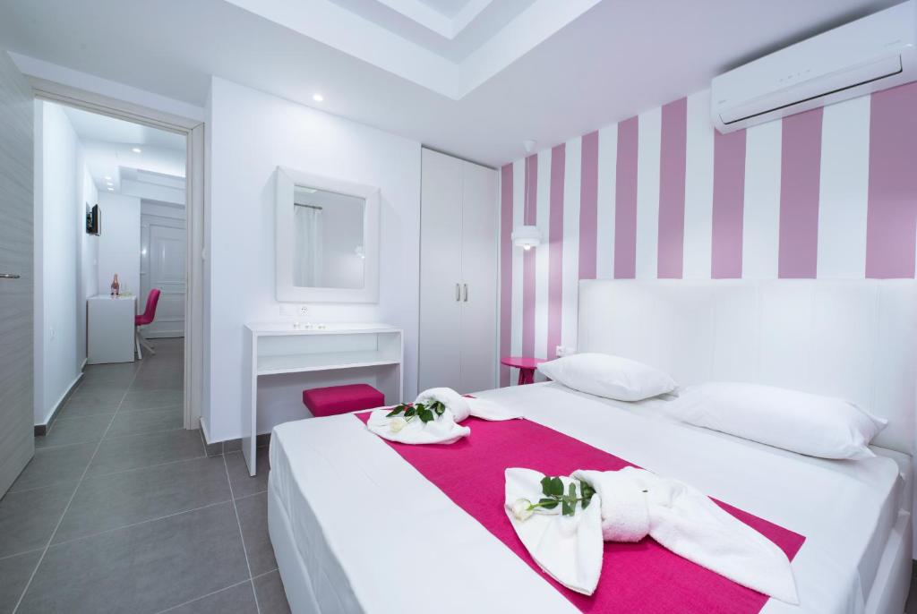 a white bedroom with a pink and white striped wall at La central Apartments in Limenaria