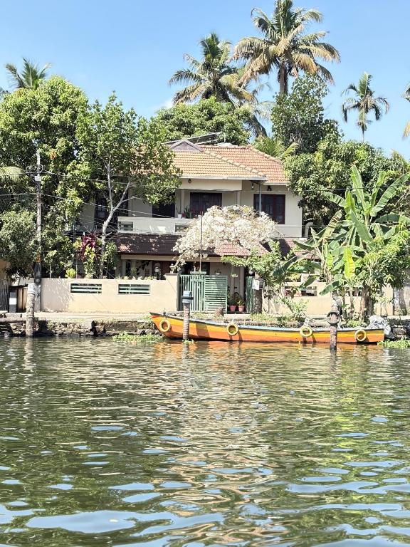 a house and a boat on the water at sacred river homestay in Alleppey
