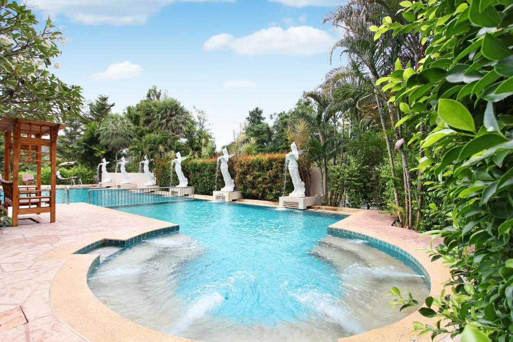 a swimming pool with statues in a garden at Nana Resort Kaeng Krachan - SHA Plus Certified in Kaeng Krachan