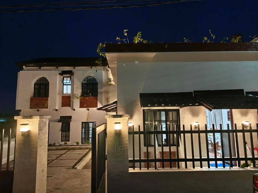 a white house with a fence at night at Serenita Tagaytay in Kibagan