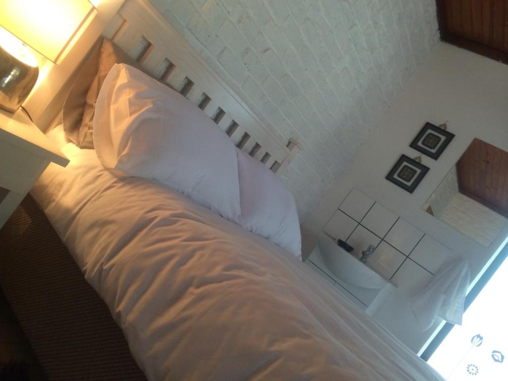 um quarto com uma cama com lençóis brancos e um candeeiro em Mopani Cottage em East London