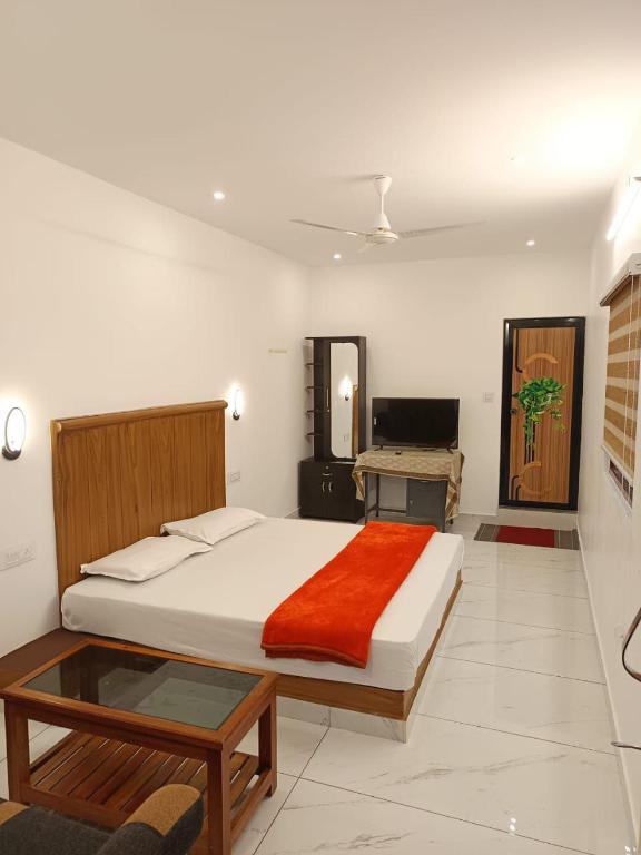 a bedroom with a large bed and a desk at Manjula Homestay in Vagamon