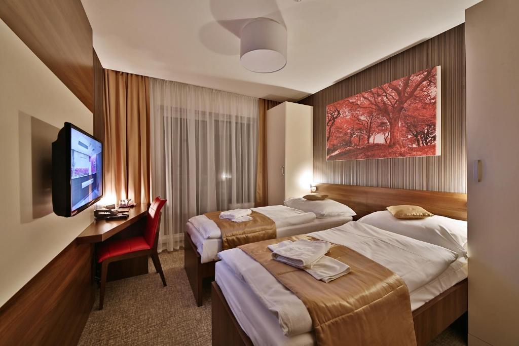 Pokój hotelowy z 2 łóżkami, biurkiem i telewizorem w obiekcie Hotel Alexander w mieście Bardejovské Kúpele