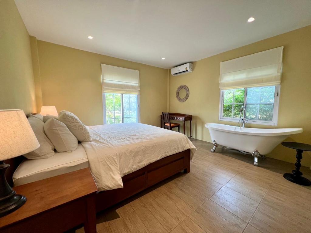 a bedroom with a bed and a bathtub and a tub at Sunset House Khao Yai in Pak Chong