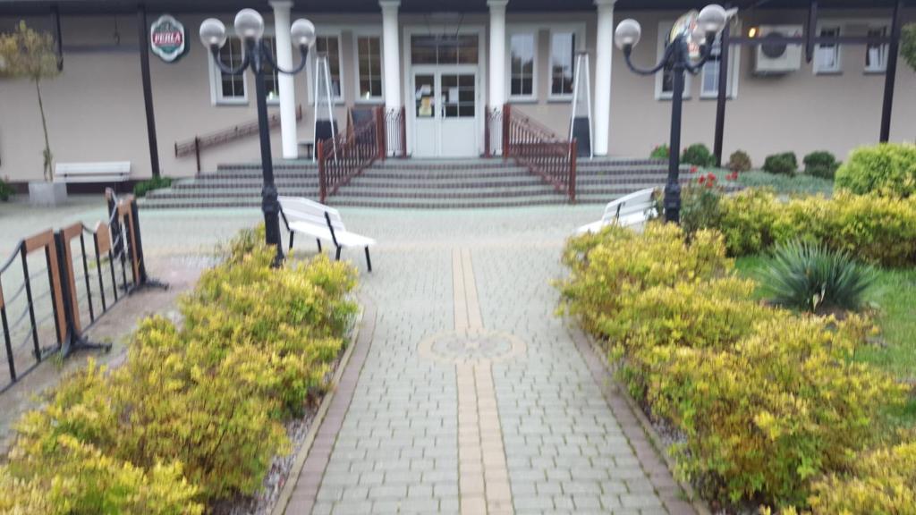 a brick walkway with benches in front of a building at Zielony Dworek in Kraśnik