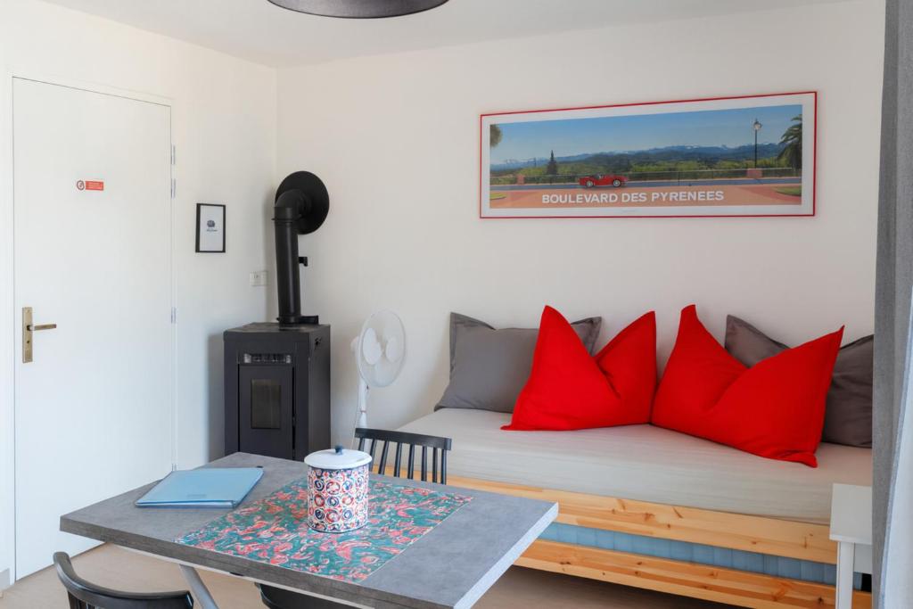 Appartement modulable في لانيميزان: غرفة نوم بها سرير ووسائد حمراء وطاولة