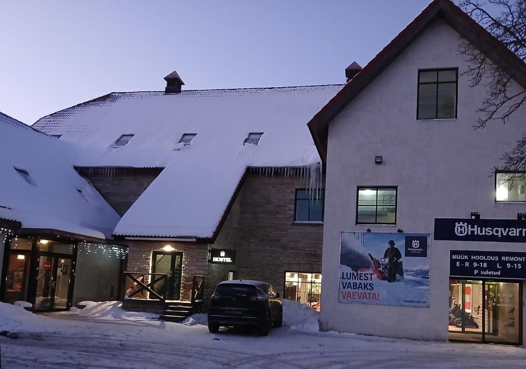 a snow covered building with a car parked in front of it at Aiakeskuse hostel in Rakvere