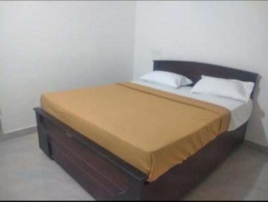 a bed with a wooden headboard and two pillows at SLP Residency in Mysore