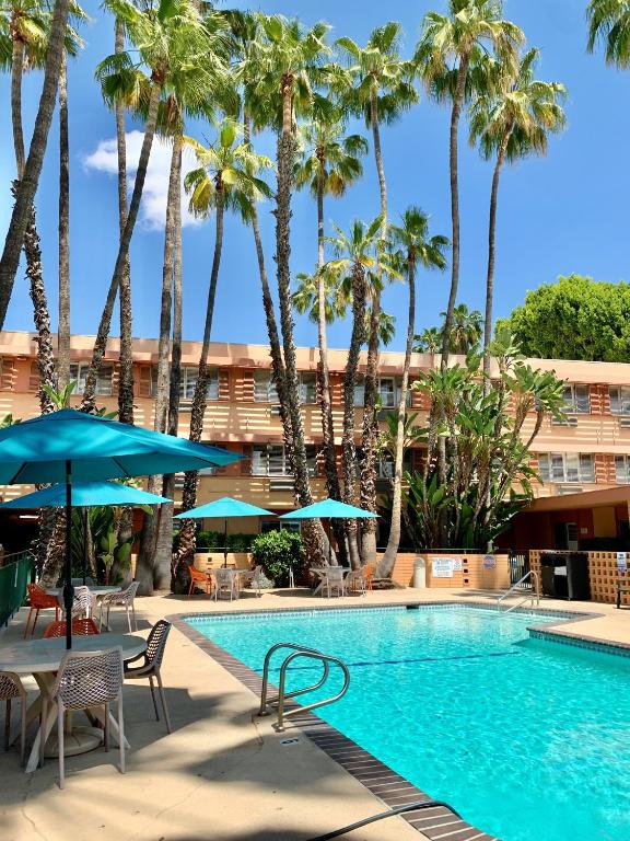 a swimming pool with palm trees in front of a hotel at Saga Motor Hotel Pasadena in Pasadena