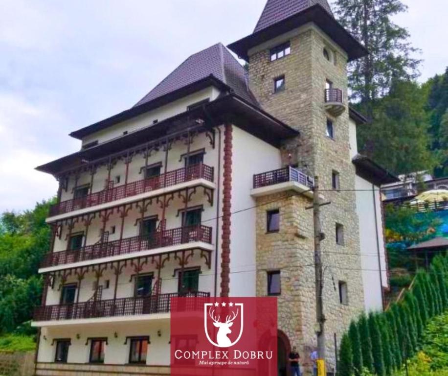 a building with a tower with a sign in front of it at VILA DOBRU in Slănic-Moldova