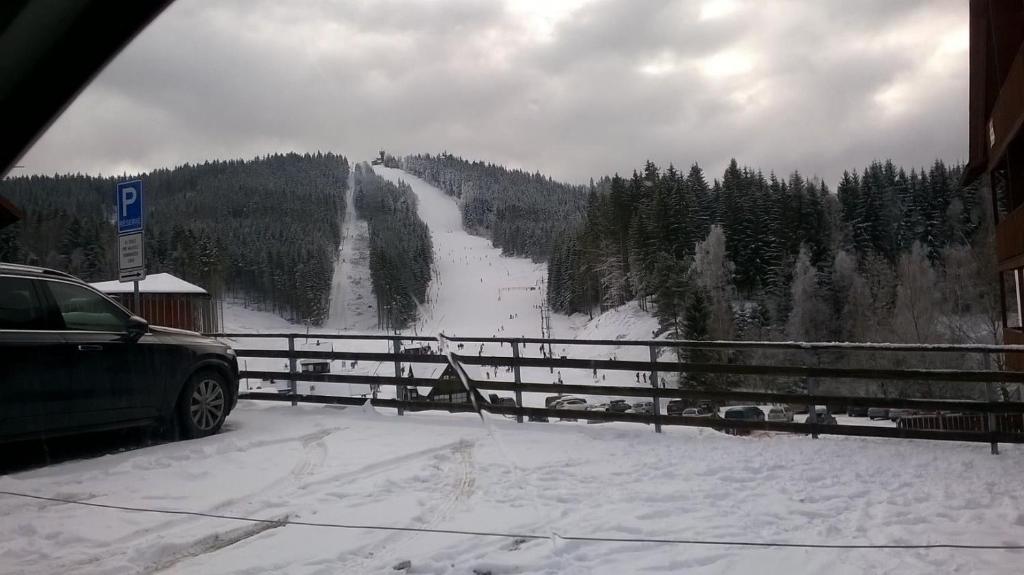 vistas a una montaña cubierta de nieve con coche en Apartmánek u Špičáku en Albrechtice v Jizerských horách