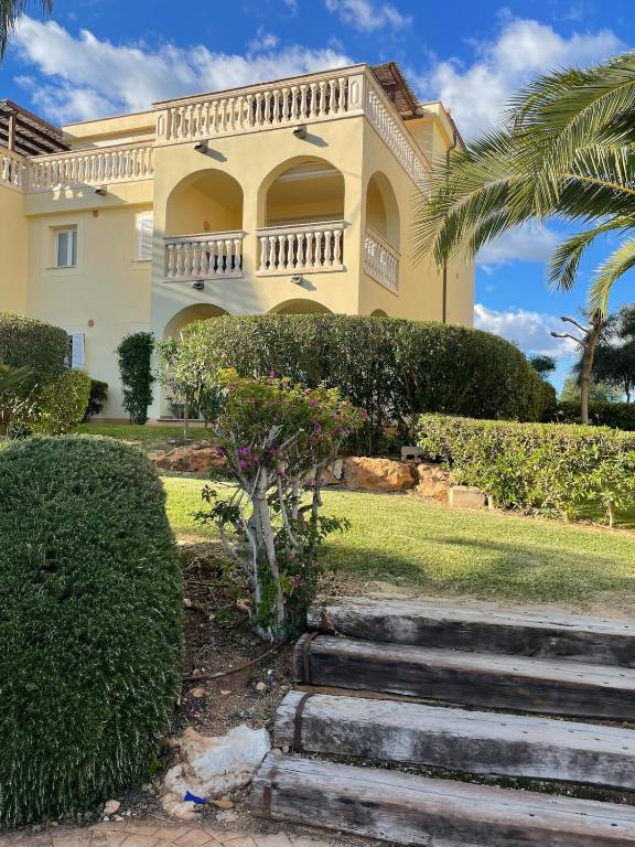 a large yellow house with a balcony and stairs at Can Chus Cala Anguila in Cala Mendia