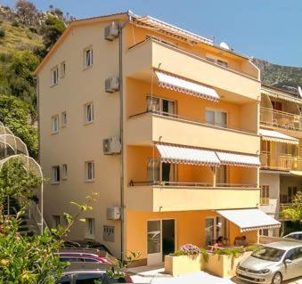 伯德古拉的住宿－Apartment Marta，一座橙色的建筑,前面有汽车停放