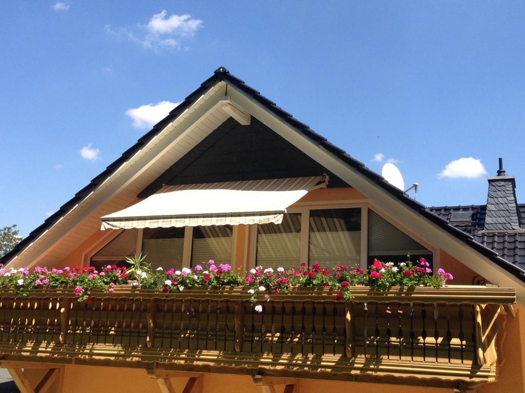 einen Balkon mit Blumen und einem Regenschirm auf einem Haus in der Unterkunft Ferienwohnung Am Eichenberg in Blankenburg