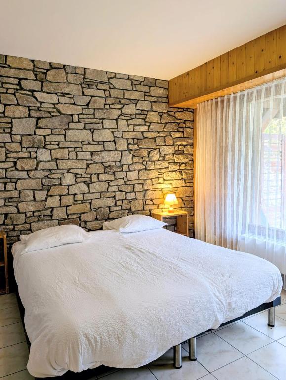 a bed in a bedroom with a brick wall at Centre Thermal studio NORD S4003 in Ovronnaz